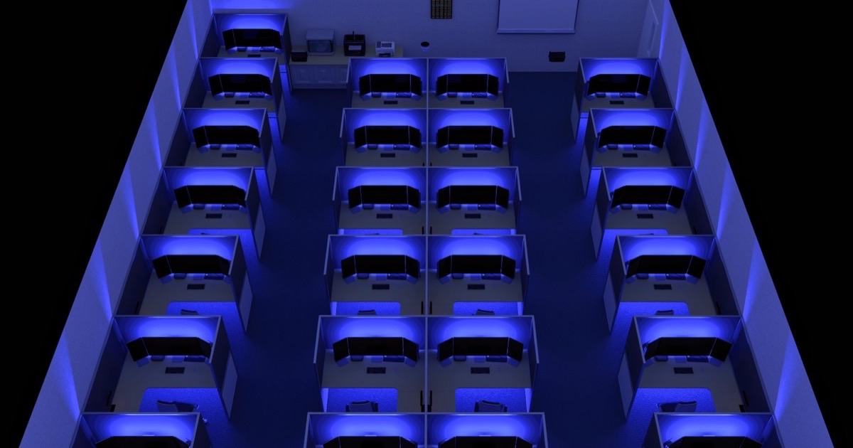 Fila de postos de trabalho num laboratório de informática de uma escola, com computadores e ecrãs alinhados